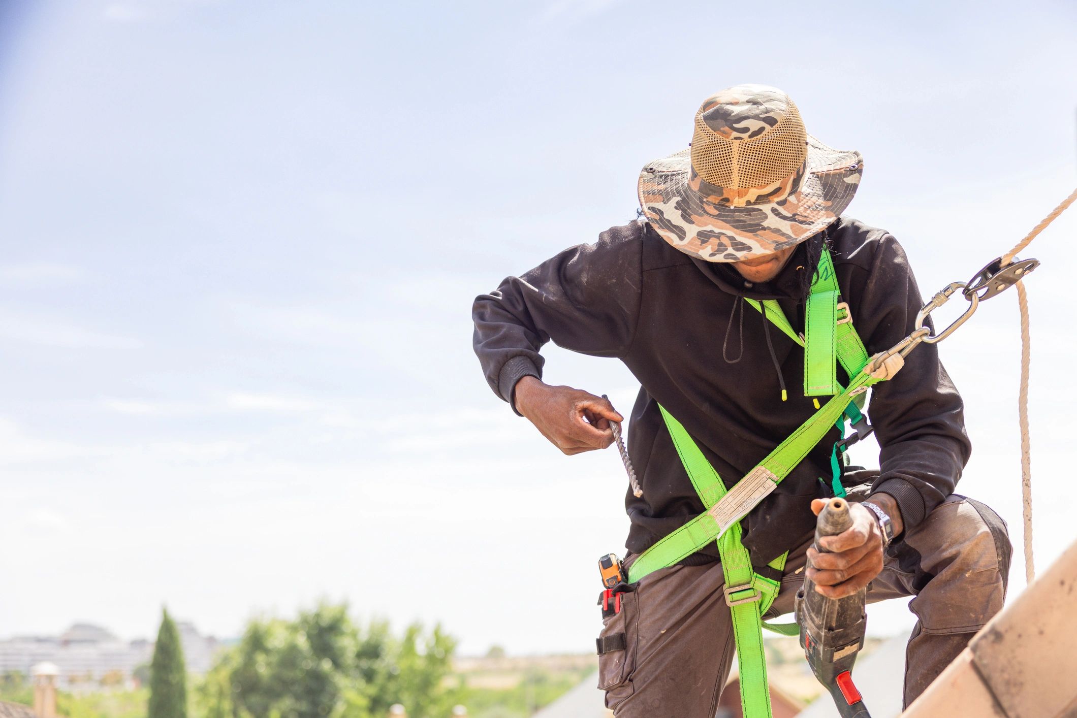 Construction worker wearing safety harness installing roof on house.